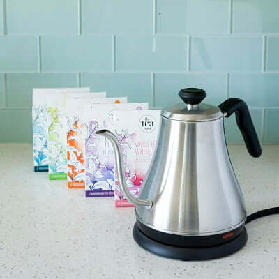 a teapot since on a countertop next to boxes of tea