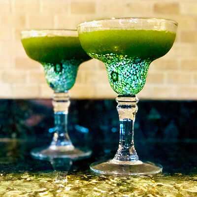 two fozen matcha margaritas sit on a marble countertop