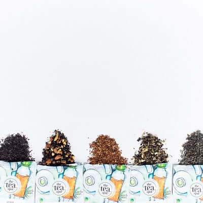 four pouches of tea spill loose leaf tea on a white background