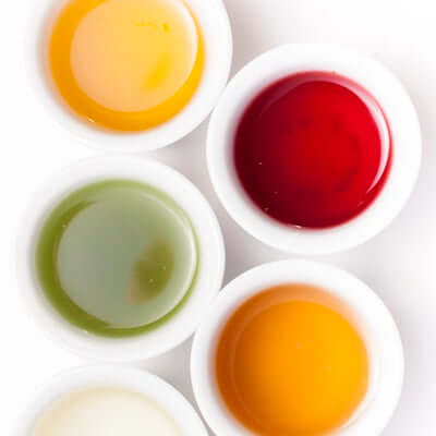 white cups of of colorful teas on a white background