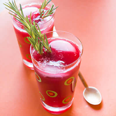 two tea mocktails sit on a peach surface next to a spoon