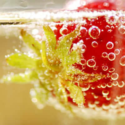 a strawberry floats in tea with bubbles