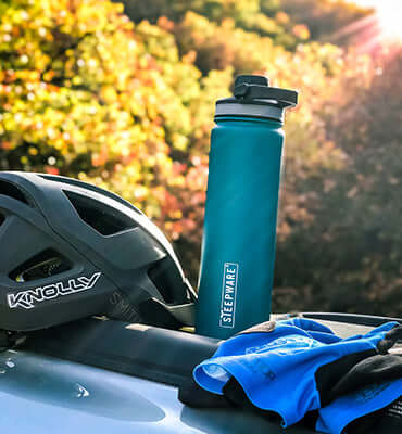 tea tumbler sits outdoors next to bicycle helmet 