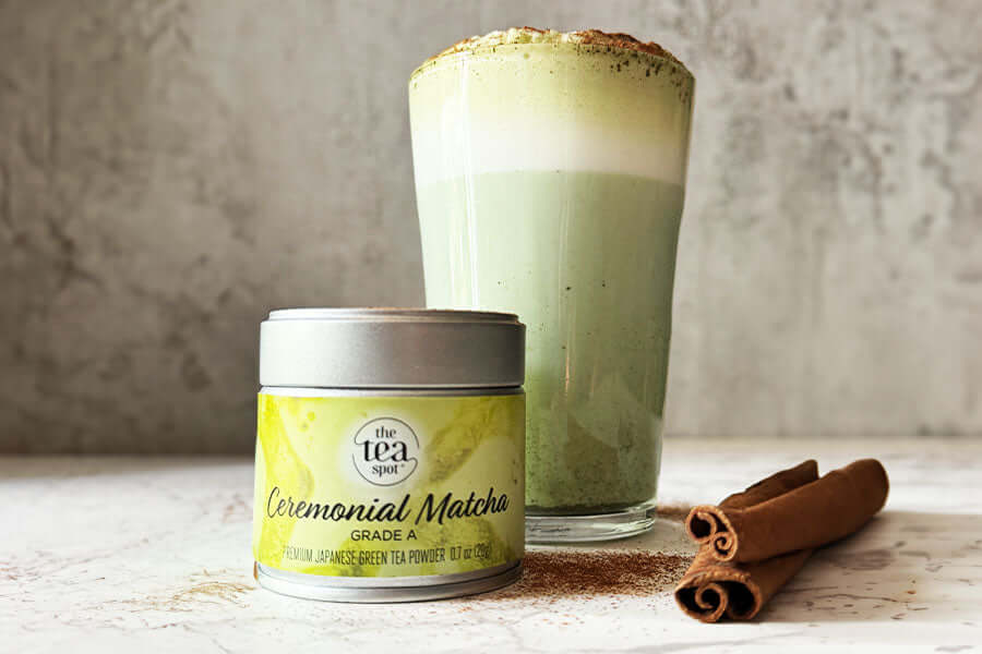 a spiced matcha latte with ceremonial matcha and cinnamon in front of it