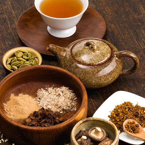 adaptogen ingredients on a wooden table next to a teapot and cup of adaptogenic tea