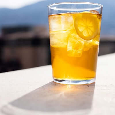 a glass of iced tea in fron of a mountain background with sunlight shining through