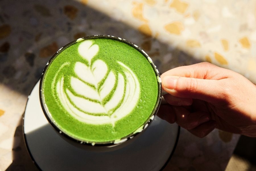 a person holds a matcha latte in their hand