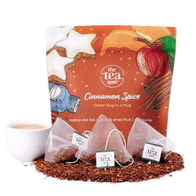 a bag reading cinnamon spice sits behind tea bags, loose leaf tea, and a tea cup