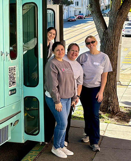 four people smile in front of a bus providing free cancer care