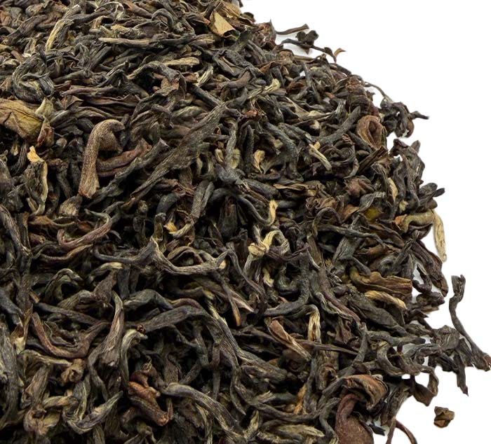 Close-up of dried black darjeeling tea leaves on a white background