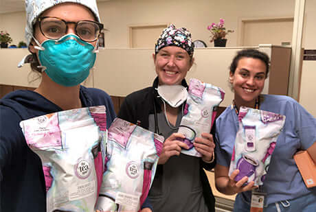 three doctors smile and hold bags of tea