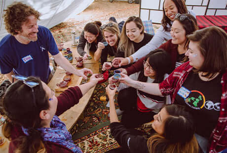 many people cheers tea cups in a tent
