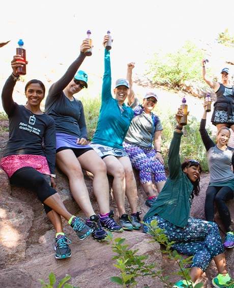 people sitting on a rock cheers tea tumblers in the air