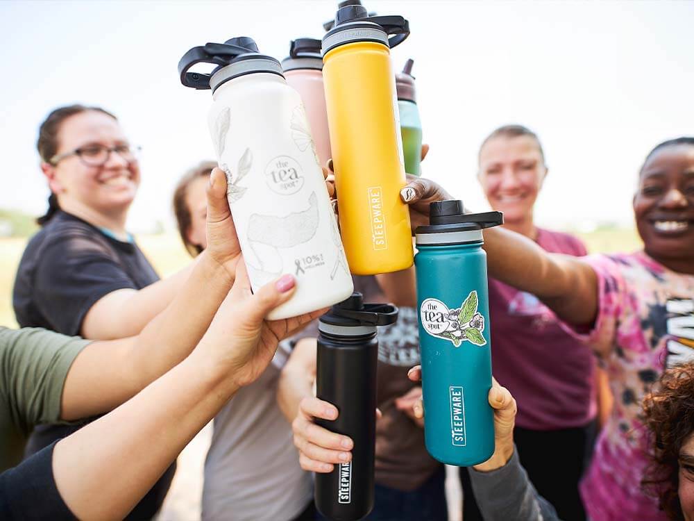 tea spot employees smile and cheers their tea tumblers together