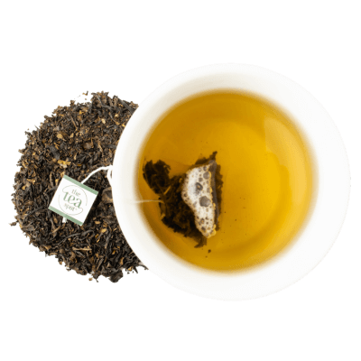 a tea cup with brewed tea and a tea bag sits next to loose leaf tea