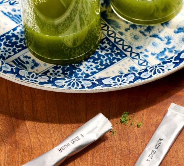 two foil packs of matcha labeled matcha grade A sit next to cups of matcha