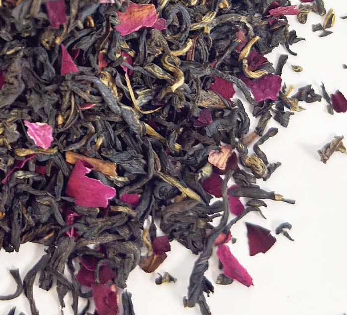 Black tea leaves with rose petals on a white background