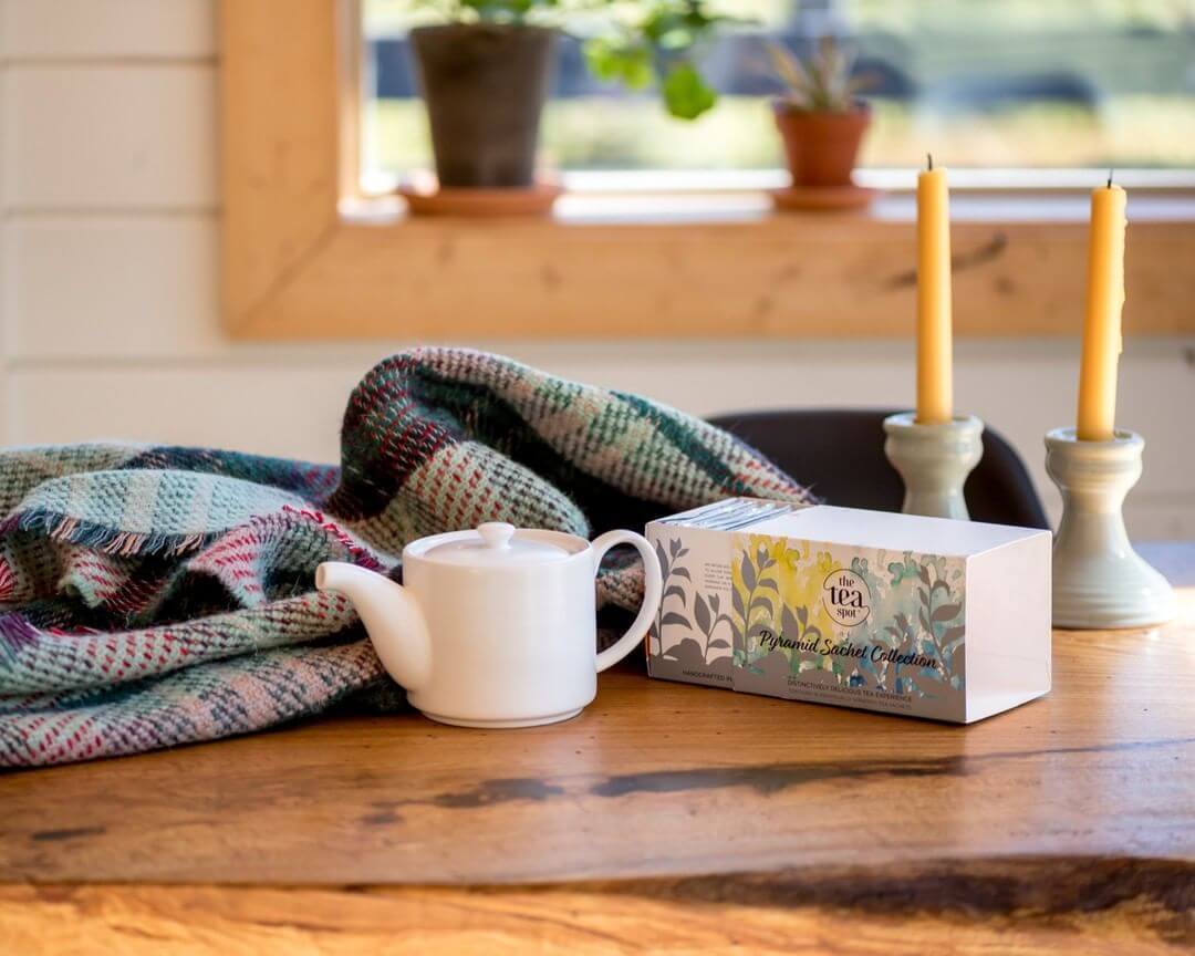 Pyramid Sachet Sample Collection on a wooden table next to teapot and candles