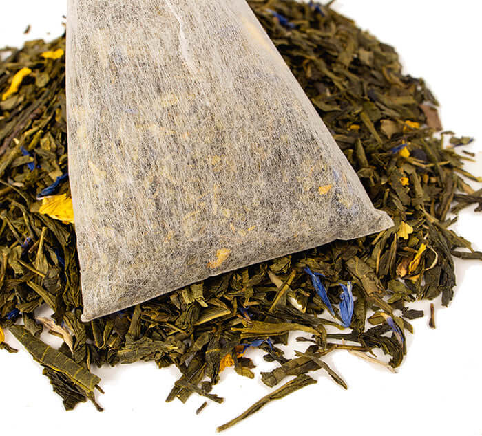 Boulder Blues Iced Tea Pouch sits on a pile of loose green tea blend