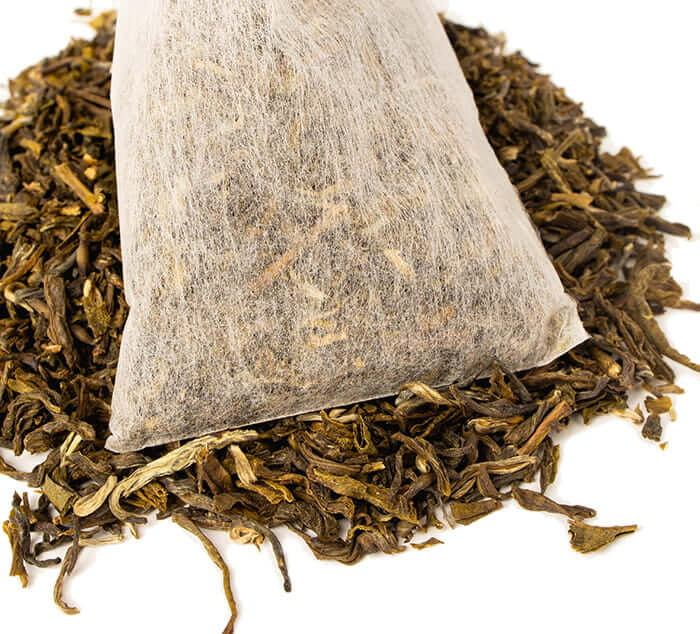 Jasmine Petals Iced Tea Bag sits ona pile of loose leaf tea