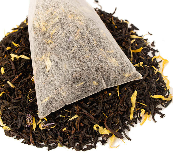 Mango Tango Iced Tea pouch sits on a pile of loose tea 