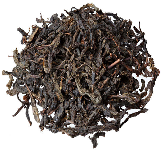 Black sundried tea leaves are arranged in a circle on a white background
